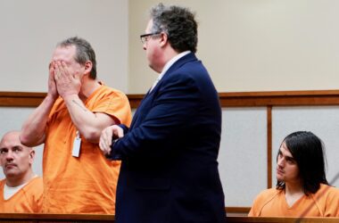 A defendant holds his face in his hands