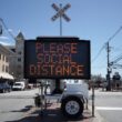 An electronic sign that reads please social distance