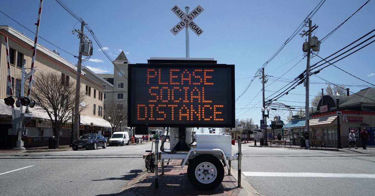 An electronic sign that reads please social distance