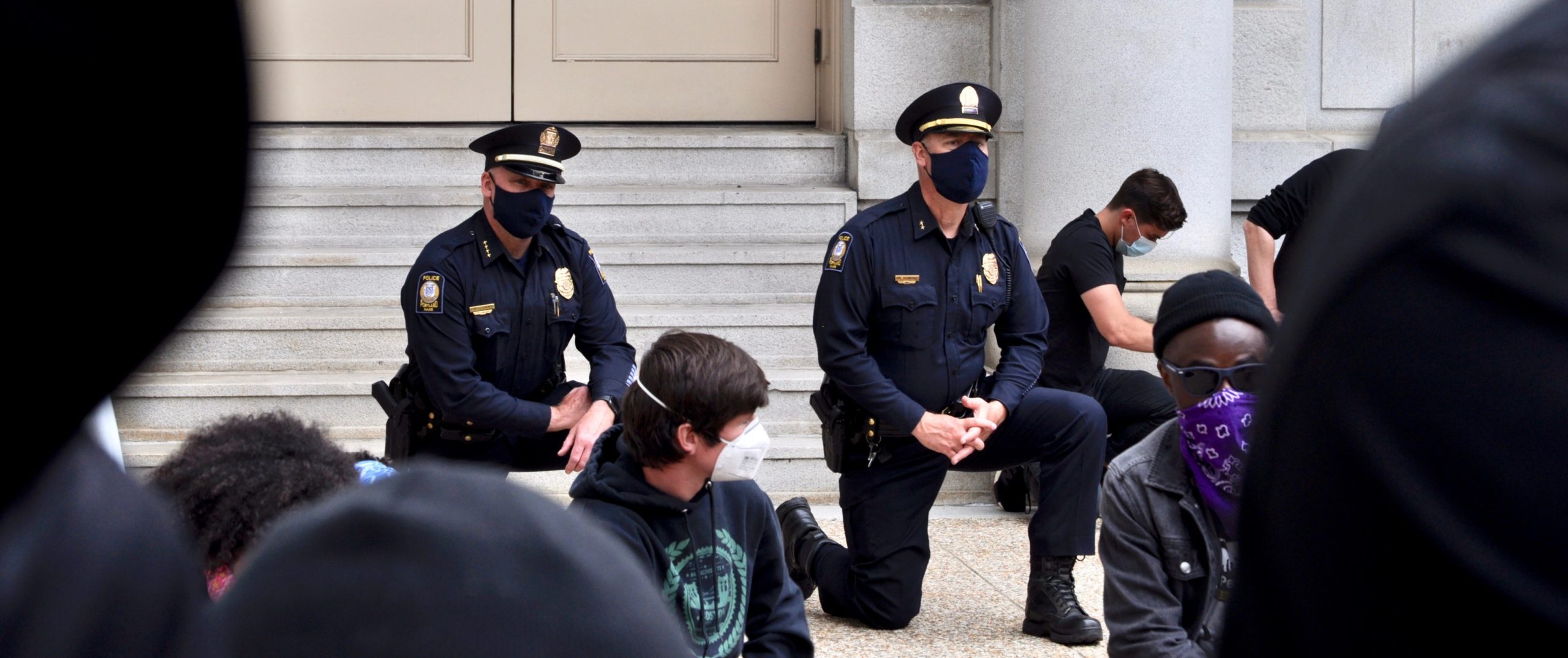 Two police officers take a knee alongside the crowd at a black lives matter rally
