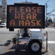 An electronic sign that reads please wear a mask