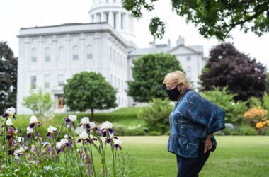 Governor Janet Mills looks at flowers growing in a garden