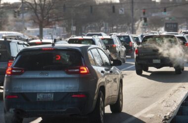 Many cars sit in backed up traffic at an intersection with a green light