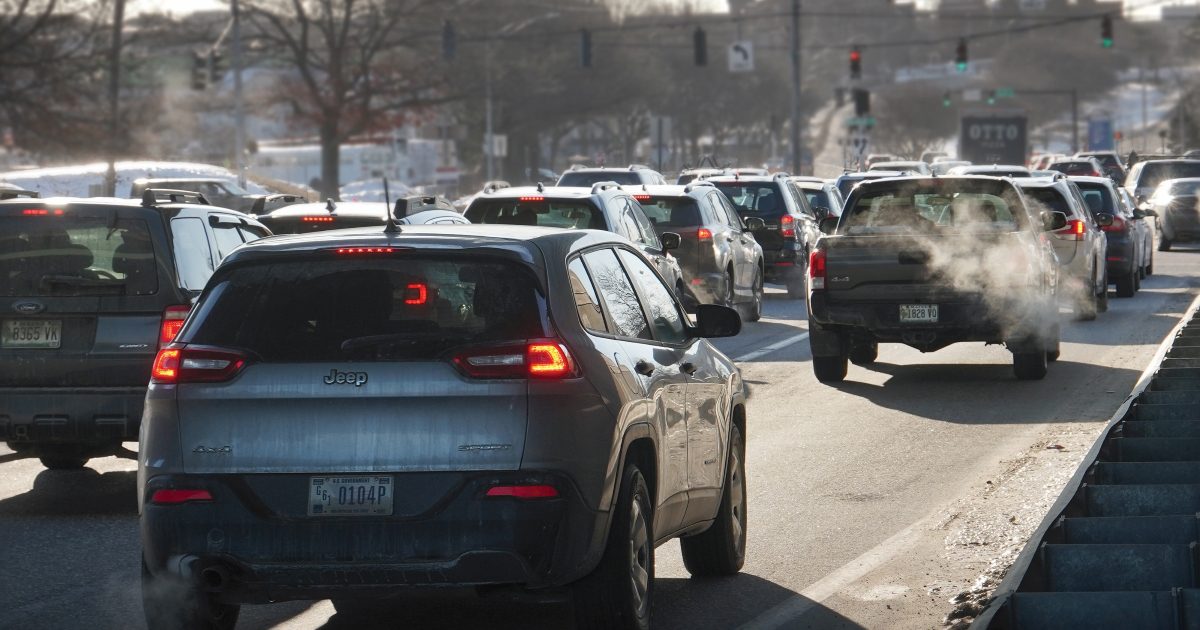 Many cars sit in backed up traffic at an intersection with a green light