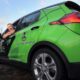 Dale Basher leans out the driver's window of a green electric vehicle belonging to Downeast Community Partners and poses for a photo.