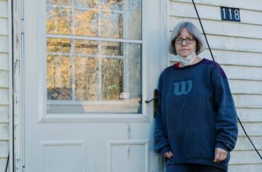 Rebecca Packard poses for a photo while leaning against her closed front door.