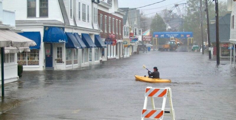 A man in a yellow kayak navigates down a flooded York street