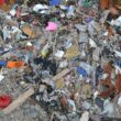 A pile of broken pieces of plastic and other trash on an otherwise sandy beach.