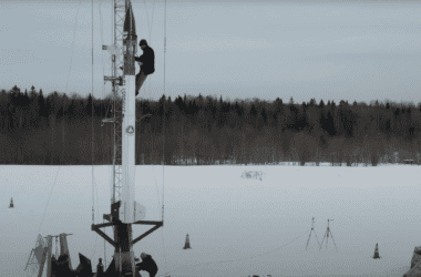 A man climbs up the length of a rocket to inspect the rock ahead of its launch.