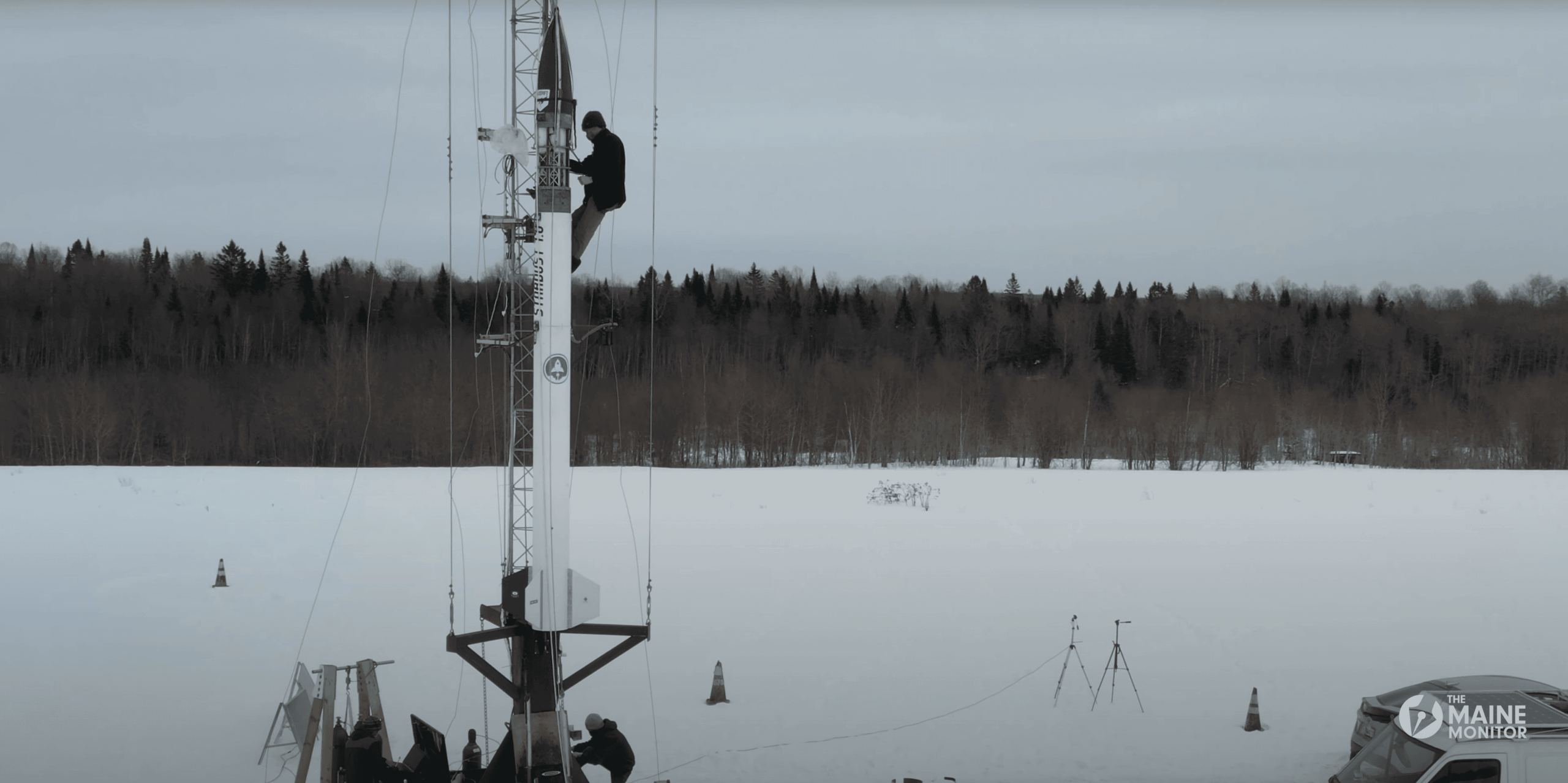 A man climbs up the length of a rocket to inspect the rock ahead of its launch.