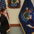 Sarah Churchill, on left, raises her right hand as she faces Governor Janet Mills, who is raising her right hand and reading from a piece of paper, during a swearing in ceremony in the governor's office.