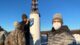 bluShift CEO Sascha Deri, on right, poses for a photo at the launch of his company's rocket. Two individuals are to the left and are checking the base of the rocket.