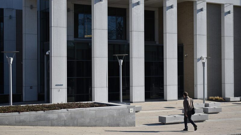 The exterior of the Capital Judicial Center. A man is walking towards the stairs of the building.