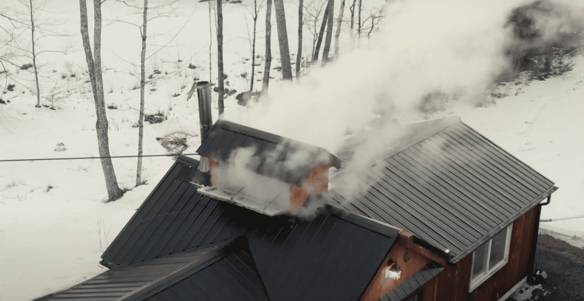 Smoke pours out of a maple making house during the maple making process in this aerial photo.