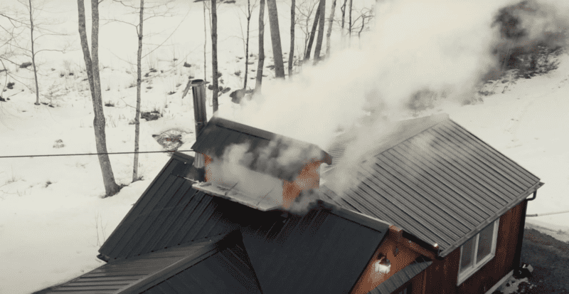 Smoke pours out of a maple making house during the maple making process in this aerial photo.