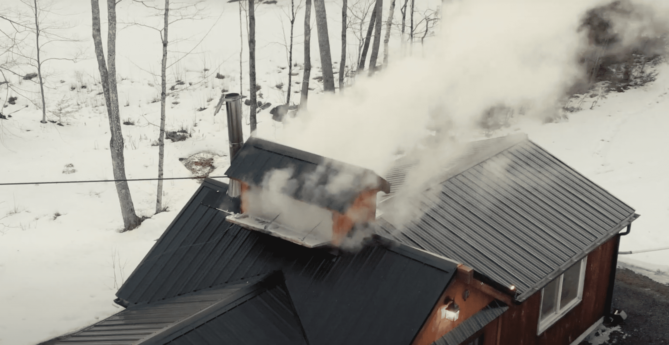 Smoke pours out of a maple making house during the maple making process in this aerial photo.