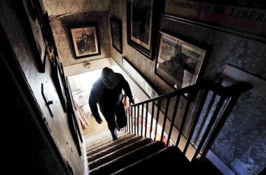 A man climbs up the stairs in an old farmhouse.