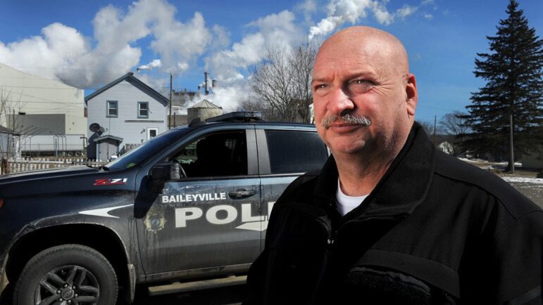 Baileyville Police Chief Bob Fitzsimmons poses for a photo with his squad car in the background.