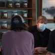 A cannabis store employee speaks to a pair of customers inside his store.