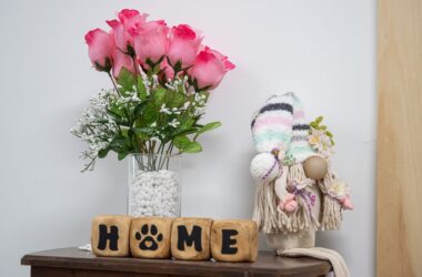 A photo of flowers and four blocks that spell out home on an end table.