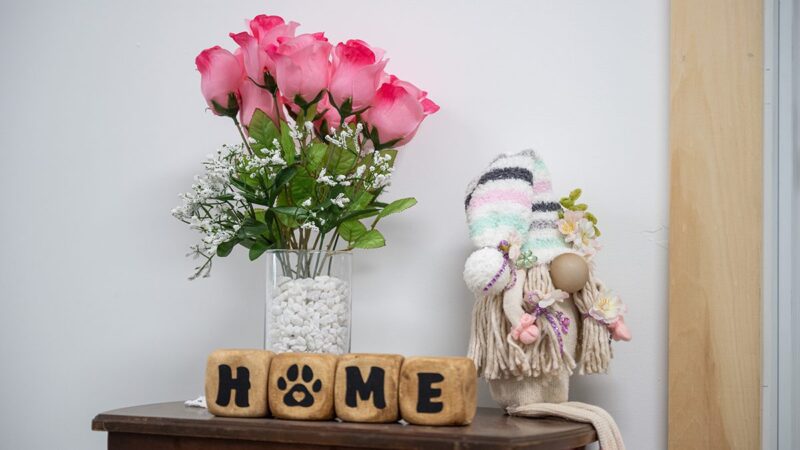 A photo of flowers and four blocks that spell out home on an end table.