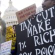 Individuals holding signs and protesting against tax cuts for the rich.
