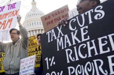 Individuals holding signs and protesting against tax cuts for the rich.