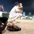 A player for the Portland Sea Dogs shows how the team is family friendly by picking up their young child on the field following a minor league baseball game