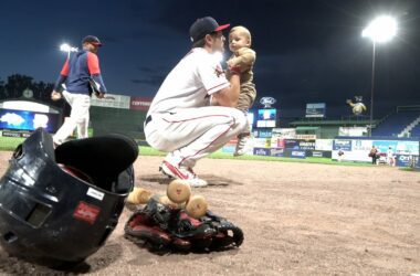 A player for the Portland Sea Dogs shows how the team is family friendly by picking up their young child on the field following a minor league baseball game