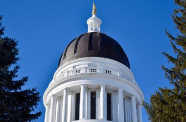 The black dome of the Maine State House stands among the trees.