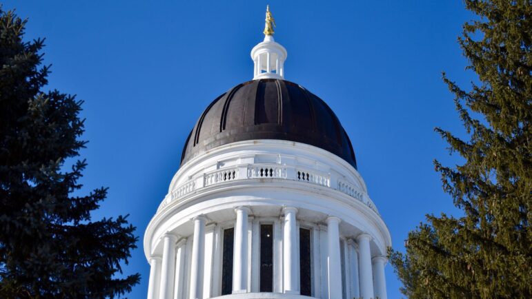 The black dome of the Maine State House stands among the trees.