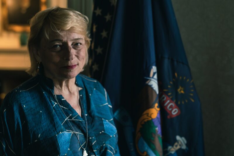 janet mills poses for a photo by the state of maine flag