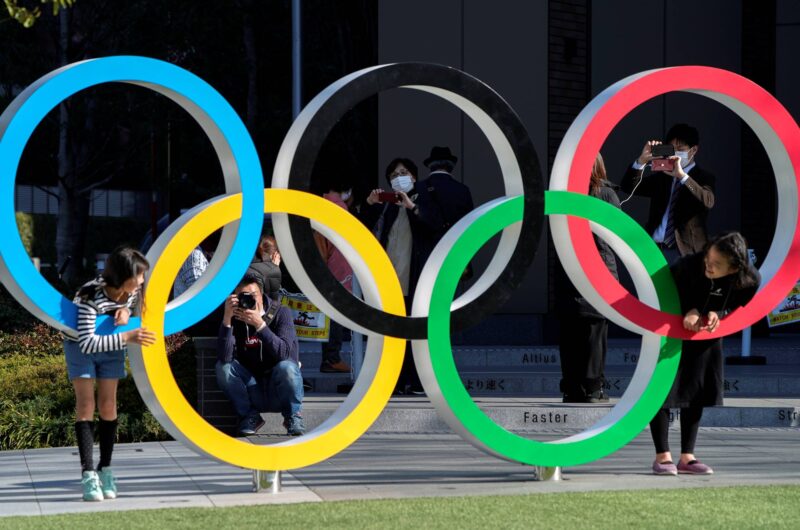 Tourists pose for a photo within the Olympic rings