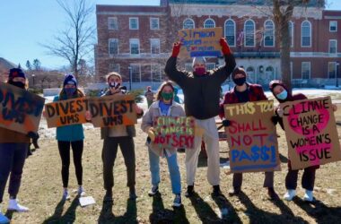 Seven college students hold signs protesting against climate change and demanding the University of Maine System divest fossil fuels from its endowment