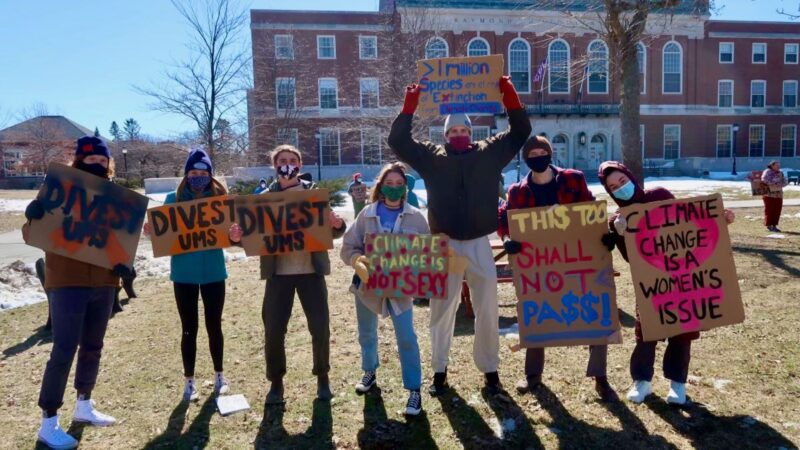 Seven college students hold signs protesting against climate change and demanding the University of Maine System divest fossil fuels from its endowment