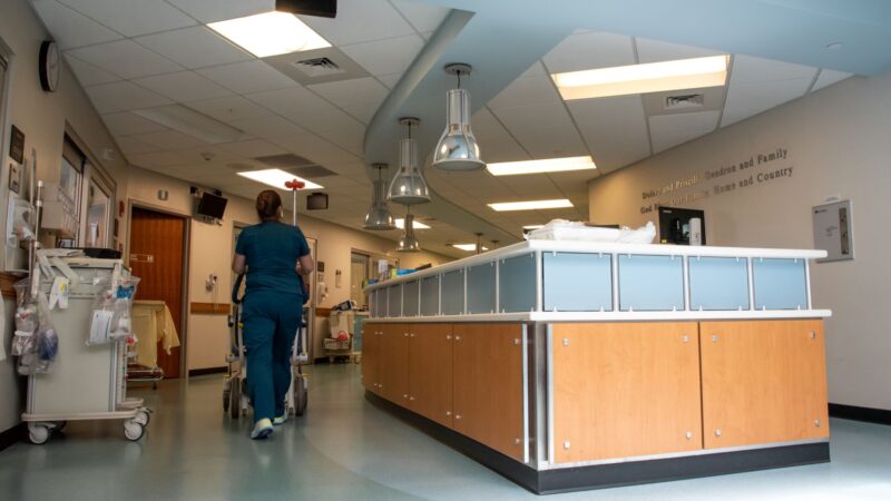 A nurse walks past a desk within the interior of a nursing home