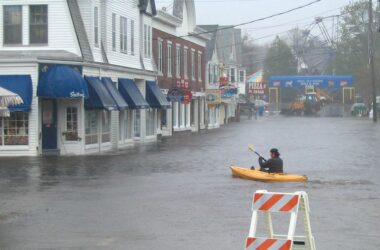 a man in a yellow kayak navigates a flooded York street