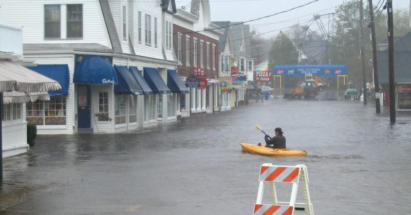 a man in a yellow kayak navigates a flooded York street
