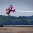 A red plane flies through the air during an air show.