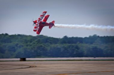 A red plane flies through the air during an air show.