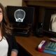 Amanda Brownell sits at her desk with a child's xray appearing on both computer monitors and a pair of child abuse books stacked upon each other on her desk.