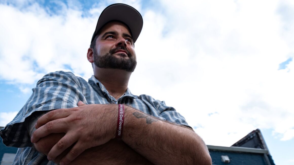 Scott Knowles looks toward the sky while wearing a God loves you bracelet.