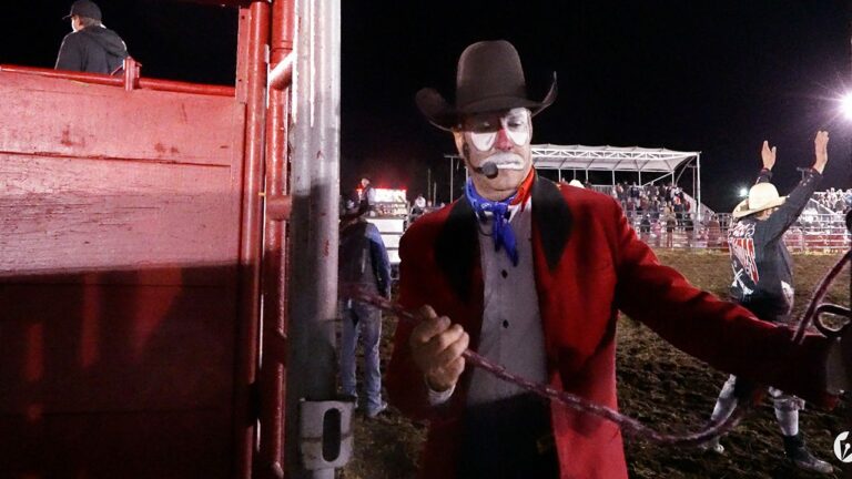 A rodeo clown exists the performance area.
