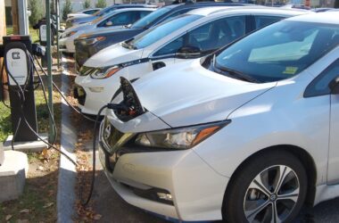 A row of electric vehicles charging in a public parking lot