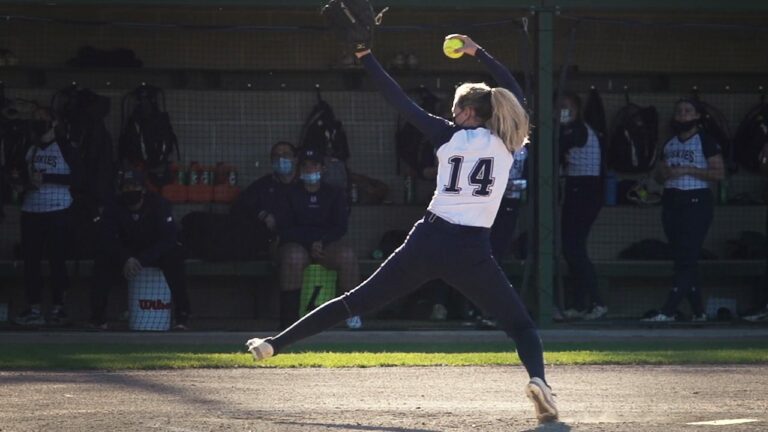 A pitcher for the University of Southern Maine softball team in the middle of her windup during a game