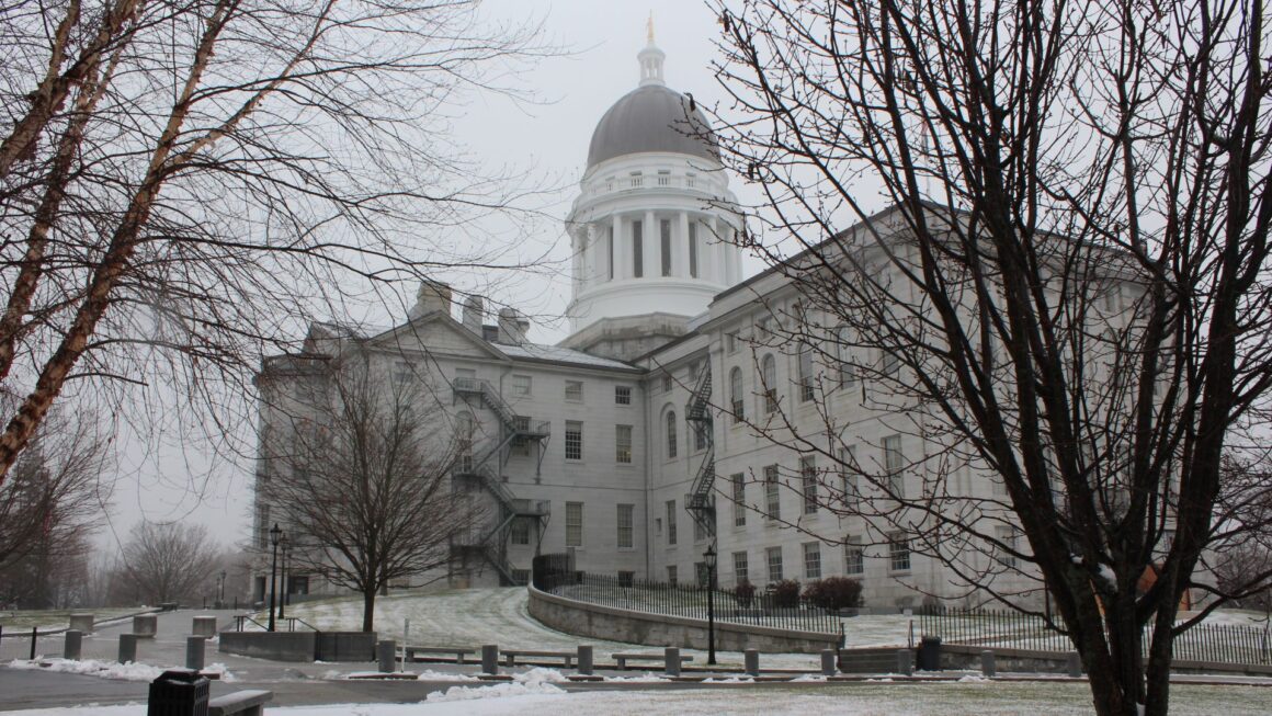 Exterior of the Maine State House in December 2021 with some remnants of snow on the ground.