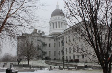 Exterior of the Maine State House in December 2021 with some remnants of snow on the ground.