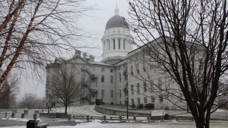 Exterior of the Maine State House in December 2021 with some remnants of snow on the ground.