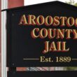 A sign for the Aroostook County Jail. The sign reads Aroostook County Jail, established 1889
