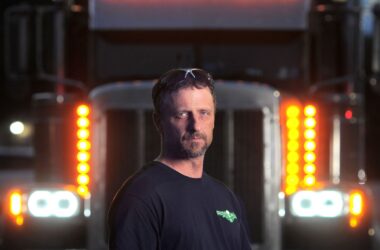 Corey Hebert poses for a photo in front of an 18-wheeler.